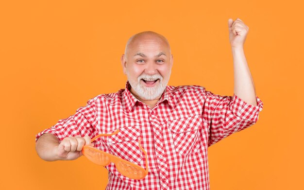 hombre viejo alegre en camisa a cuadros con gafas de fiesta en fondo amarillo