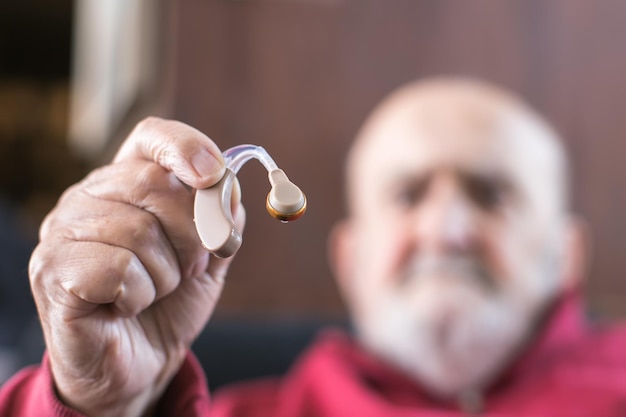 Hombre viejo con un audífono en la mano