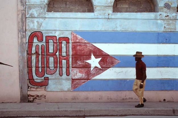 Hombre viejo en las calles de La Habana bandera cubana pintada en una pared Cuba