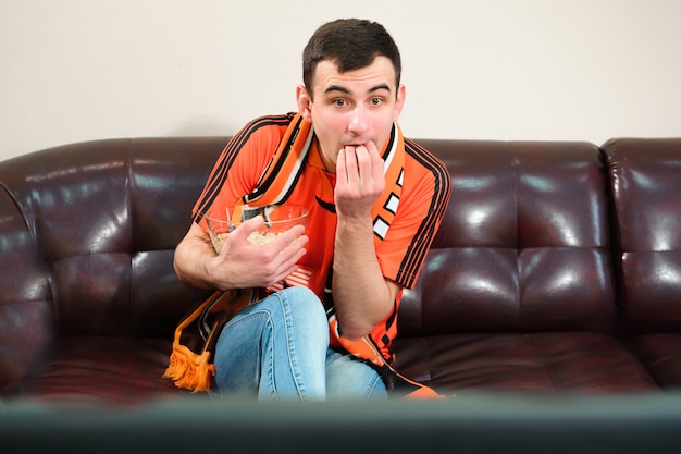 Hombre viendo fútbol, fanático del fútbol en el sofá.