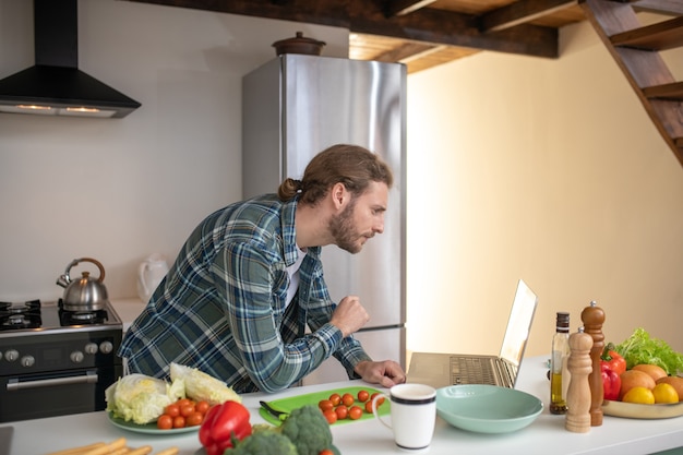 Un hombre viendo videos tutoriales sobre cómo cocinar una ensalada.