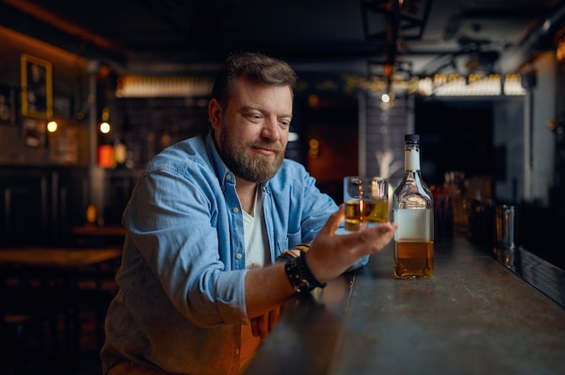 El hombre vierte alcohol en el mostrador de la barra. Una persona del sexo masculino descansando en el pub, las emociones humanas y las actividades de ocio.