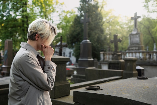 Hombre visitando una tumba en el cementerio