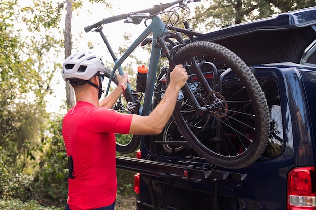 Hombre vistiéndose junto a su furgoneta para ir en bicicleta