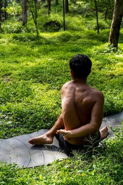 Hombre visto de cerca sin camisa haciendo estiramientos en ejercicio de colchoneta de yoga latinoamérica