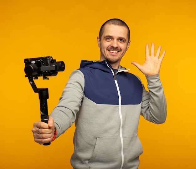 Hombre vlogger o video blogger sosteniendo la cámara en el cardán y sonriendo en la cámara de pie