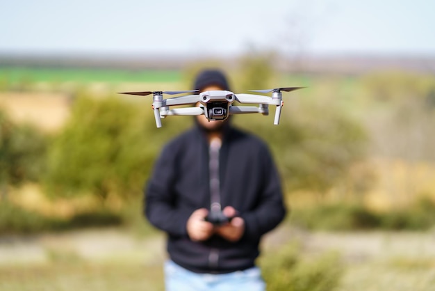 Hombre volando un dron frente a él y cubriendo su rostro