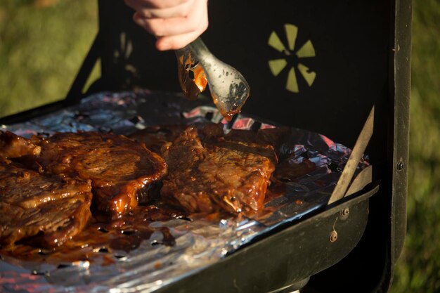 Foto hombre volviendo filetes mientras se cocinan en una parrilla