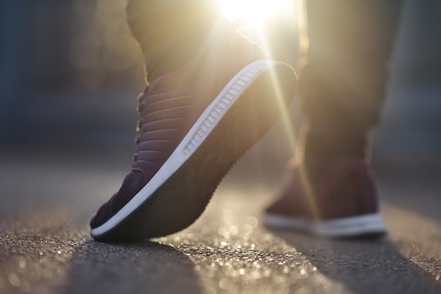 Hombre en zapatillas camina por la calle en un día soleado