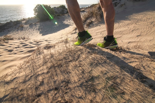 Un hombre con zapatillas de deporte degradadas amarillas y negras. De pie en el borde de un acantilado.