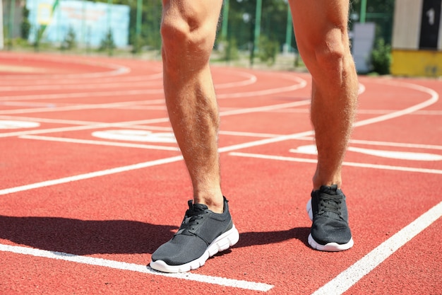 Hombre en zapatillas de deporte en la pista de atletismo roja, cerrar