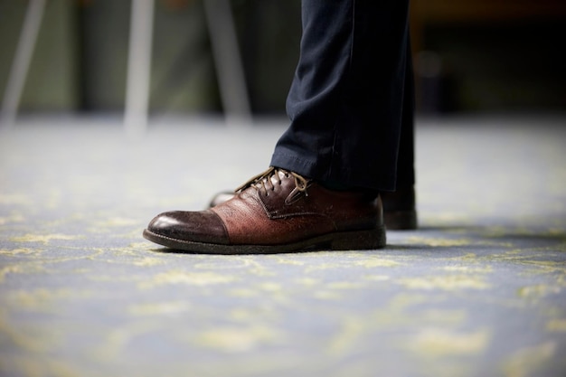 hombre con zapatos de cuero marrón en el interior, primer plano de las piernas. Primer plano de zapatos de hombre marrón caro en pantalones azules