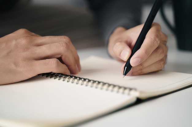 Hombre zurdo escribe en un cuaderno sobre la mesa