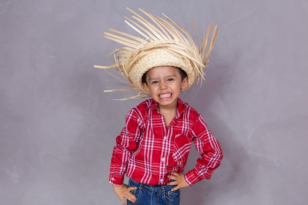 Hombrecito con ropa típica de fiesta de junio Niño con ropa típica de la famosa fiesta brasileña llamada Festa Junina en celebración de Sao Joao Hermoso hombre sobre fondo gris