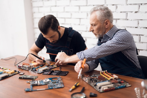 Hombres adultos y jóvenes reparan piezas de la computadora juntos