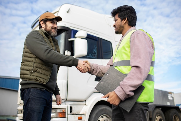 Hombres de ángulo bajo dándose la mano