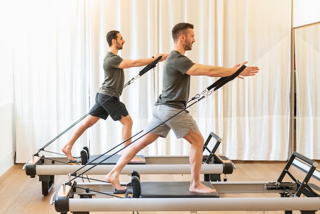 Hombres aptos haciendo ejercicio en máquinas de pilates en el gimnasio