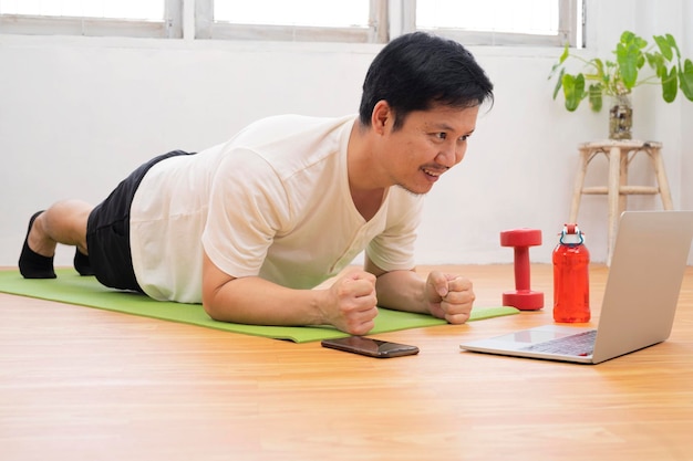 Hombres apuestos que practican deportes en casa en el concepto de estilo de vida saludable de la alfombra