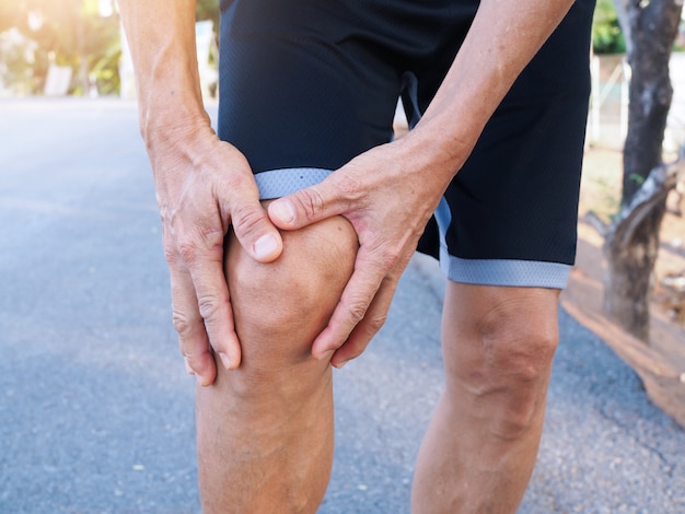 Foto hombres asiáticos de edad avanzada con dolor en la rodilla y dolor muscular por el ejercicio al correr.