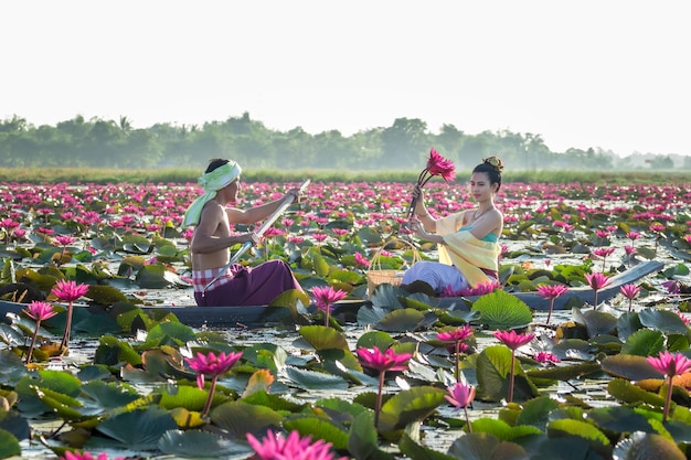 Foto hombres asiáticos están recogiendo flores de loto rojas para que las mujeres asiáticas adoren