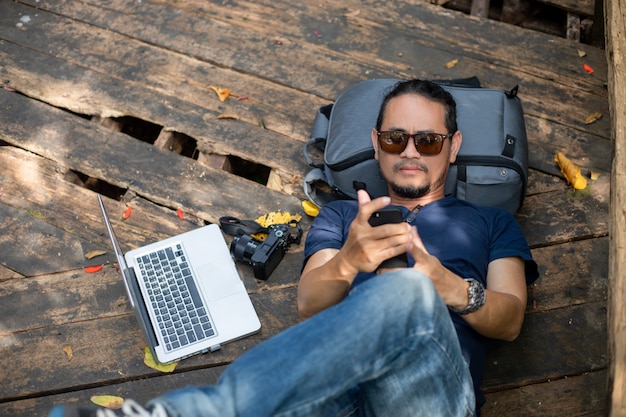 Hombres asiáticos mochilas y viajeros que trabajan en la computadora portátil en la naturaleza al aire libre y él se relaja y disfruta de los viajes