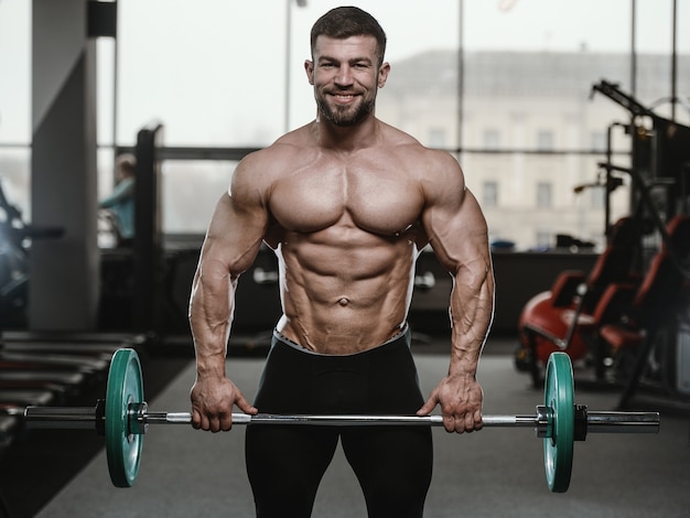 Hombres atléticos brutales culturistas fuertes bombeando músculos con pesas