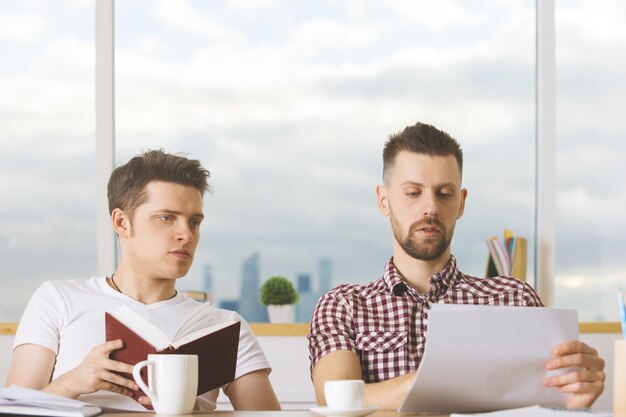 Hombres atractivos leyendo libros y haciendo trámites