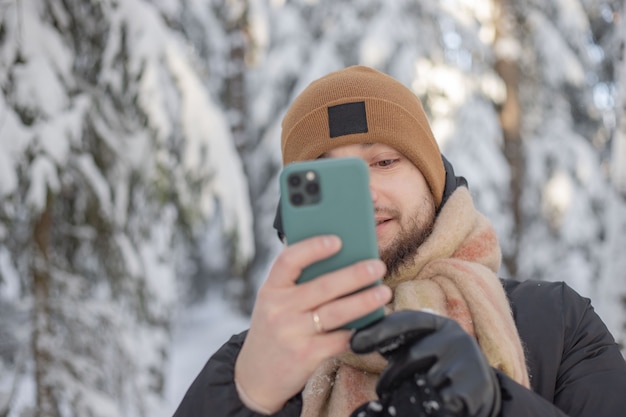 los hombres en el bosque de invierno sostienen el teléfono móvil en las manos