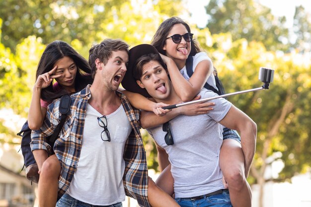 Foto hombres de cadera que dan a sus amigas y que toman autofotos en la calle.