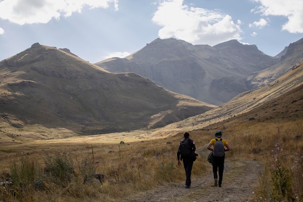 Los hombres caminan en las montañas a lo largo de un camino de tierra