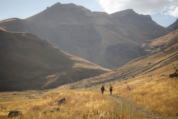 Los hombres caminan en las montañas a lo largo de un camino de tierra