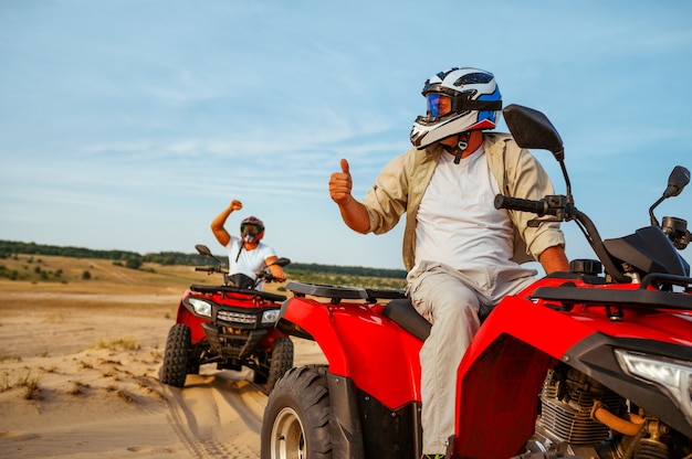 Hombres con cascos en atv, libertad montando en el desierto