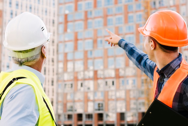 Hombres con cascos y chalecos de seguridad mirando al edificio