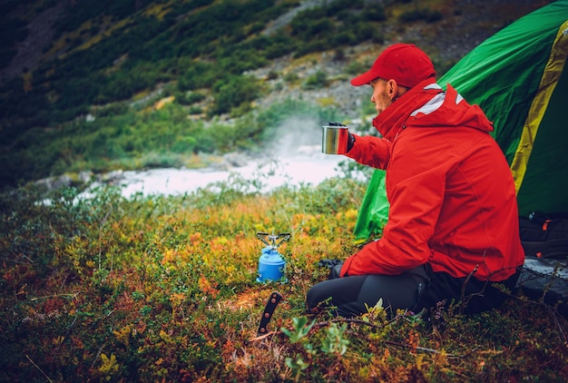 Hombres caucásicos calentándose bebiendo té caliente frente a su campamento en el desierto