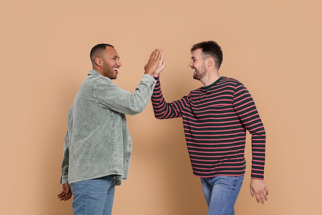 Foto hombres chocando los cinco con fondo beige