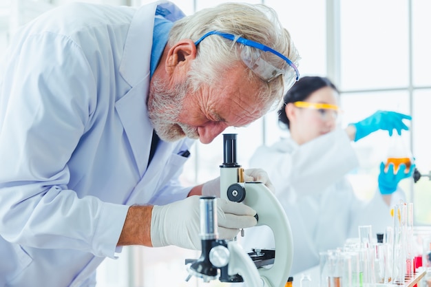 Hombres de ciencia trabajando con microscopios químicos en laboratorio