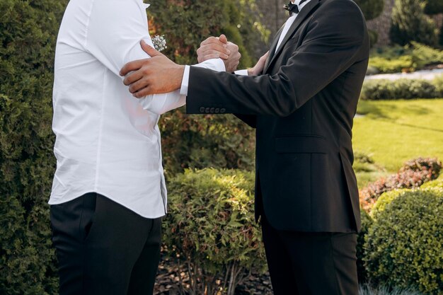 Foto hombres clásicos con estilo que se dan la mano y se apoyan el uno al otro.