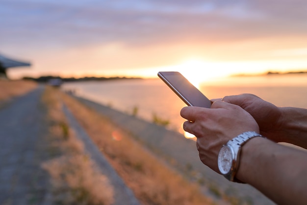 Hombres de Closeup con smartphone al atardecer