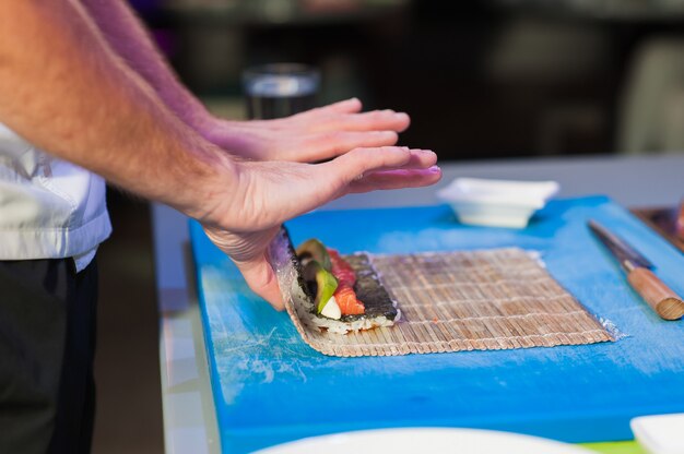 Hombres cocineros preparando sushi