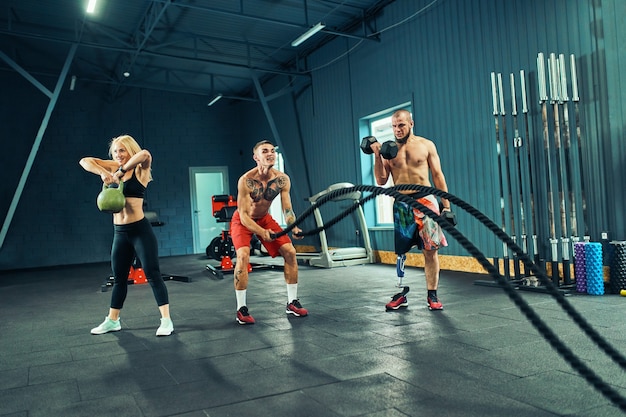 Hombres con cuerda de batalla en entrenamiento funcional fitness en gimnasio