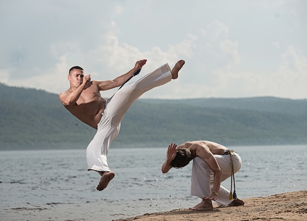 Hombres entrenan capoeira en la playa