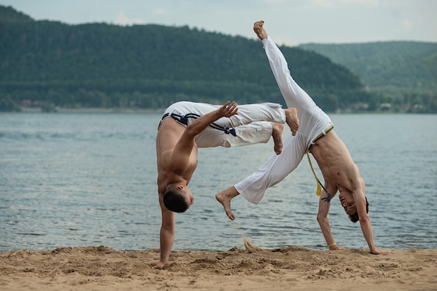 Hombres entrenan capoeira en la playa