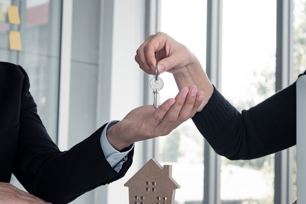 Los hombres están recibiendo la llave de casa después de comprar una casa exitosa.