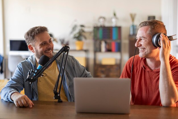 Foto hombres en un estudio de grabación con auriculares portátiles y micrófono influencer de podcast