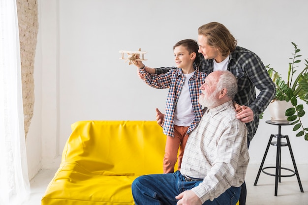 Foto hombres de familia de diferentes generaciones sostienen modelo de avión.