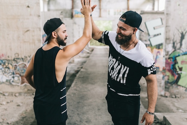 Hombres felices alto-fiving en el edificio abandonado