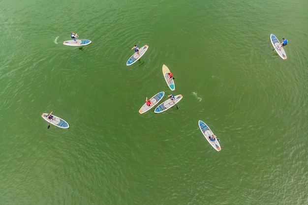 Hombres fuertes flotando en tablas de SUP en una hermosa bahía en un día soleado Vista aérea de los hombres cruza la bahía usando el paddleboard Competiciones de deportes acuáticos