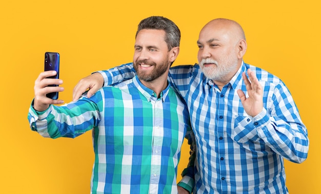 Hombres de generación hacen selfie aislado en amarillo hola hombres de generación hacen selfie en estudio