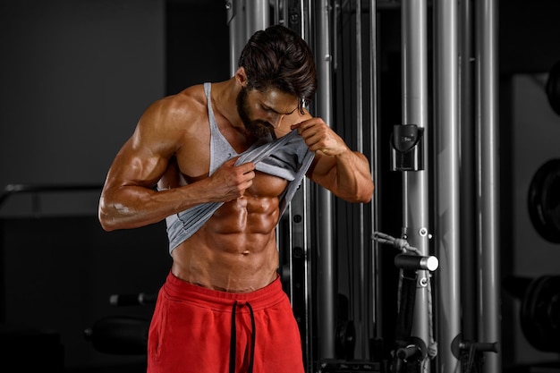 Hombres guapos con abdominales en el gimnasio mostrando el control de los músculos abdominales