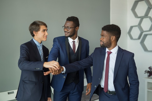 hombres guapos en traje en la oficina dándose la mano